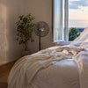 Schlafzimmer in der Abenddämmerung mit offenem Fenster und Ventilator